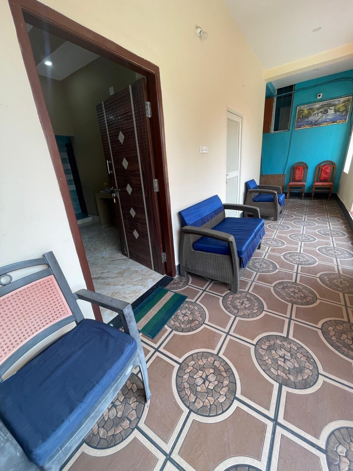 Una habitación con piso estampado, una puerta y dos sillas de mimbre con cojines azules.