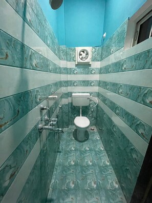 Casa de banho com sanita, secador de mãos e ventoinha.