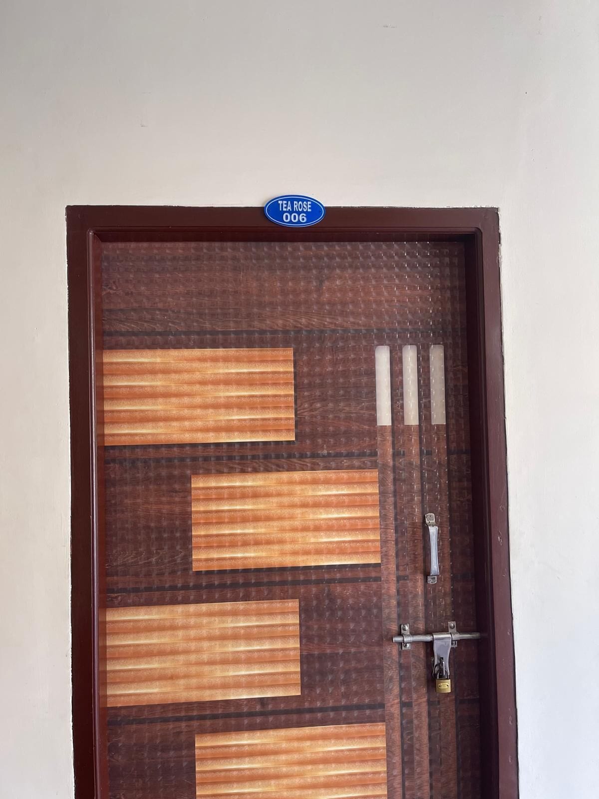 A wooden door with a sign above it, a metal handle, and a padlock.