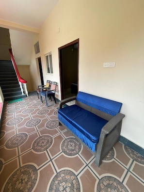 A hallway with a patterned floor, a sofa, a chair, a staircase, and a door.