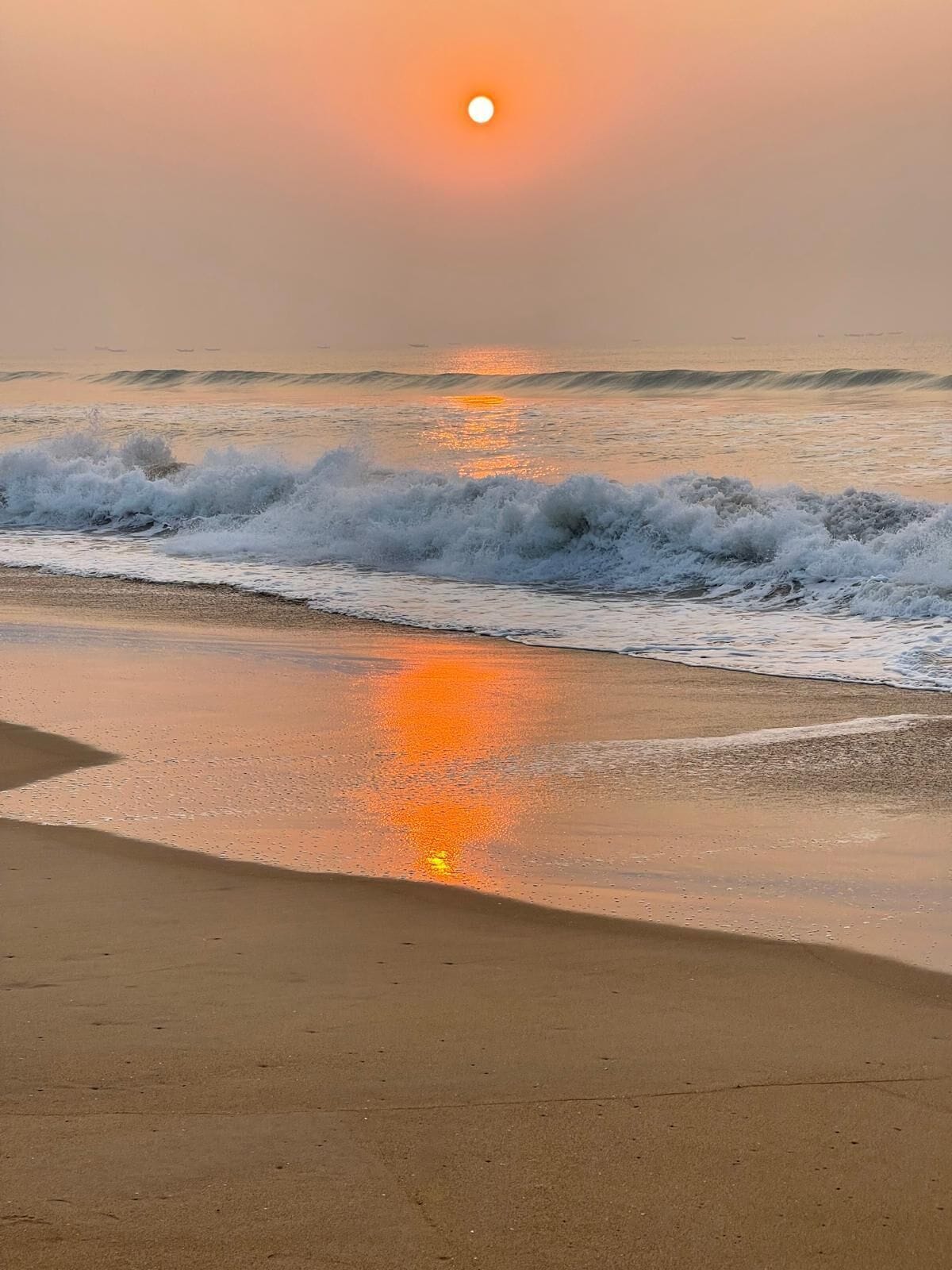 A beach with waves and a sunset.