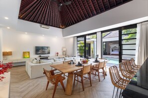 Ein modernes Wohnzimmer mit einem Holzesstisch und Stühlen, einem Sofa und einem Fernseher.