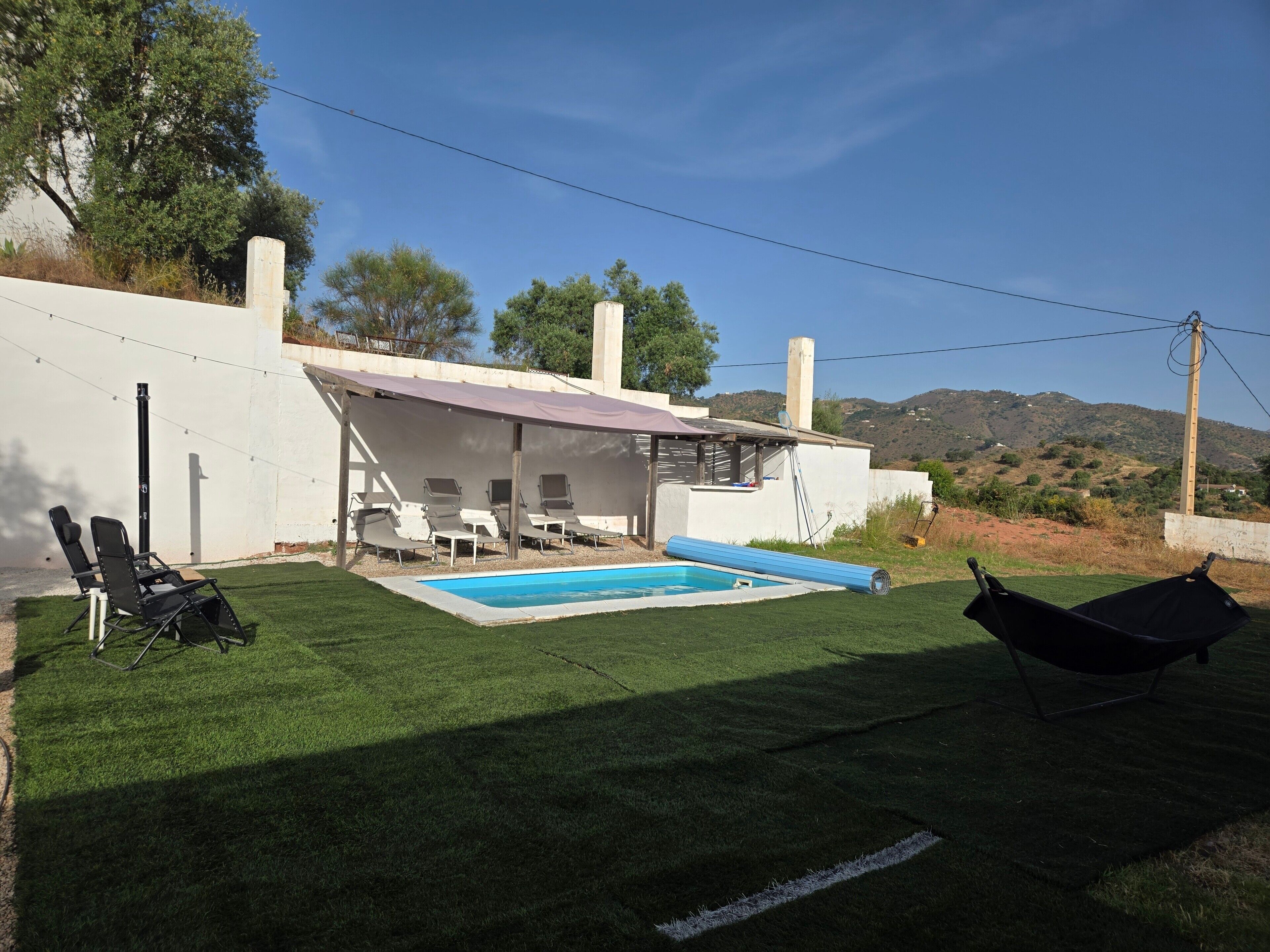 Ein Garten mit Swimmingpool, Liegestühlen und einer Hängematte.