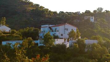 A hillside residential area with multiple white buildings, including a prominent two-story house with a red roof.