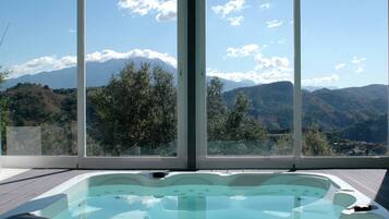 A hot tub with a mountain view through large windows.