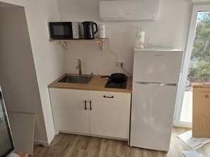 Eine kleine Küche mit Mikrowelle, Wasserkocher und Kühlschrank.