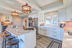 A modern kitchen with white cabinetry, stainless steel appliances, and a large island with stools. - Fort Awesome Ocean front, Lighthouse view, Agate Beach Newport Oregon (Newport)