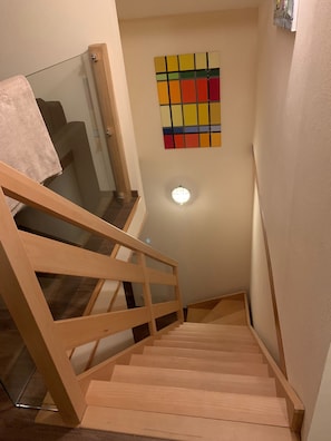 Un escalier en bois avec une rampe en verre menant à un palier.