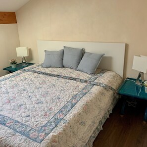 Un lit avec une couette à motifs floraux, une tête de lit en bois et deux tables de chevet avec des lampes.