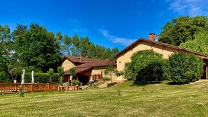 Ein Haus mit einer Stein-Fassade, einem geneigten Dach und einem umzäunten Garten mit Blumentöpfen.