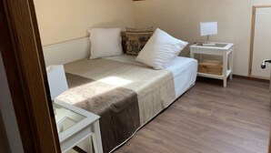 Ein Schlafzimmer mit einem Bett, einem Nachttisch, einem Schreibtisch und einer Tür.