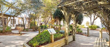 A wooden deck with planters, a pergola, and a bench.