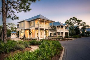 A two-story house with a balcony and a covered porch, surrounded by a landscaped garden. - New! WaterColor, w/ Private Pool, Spa, & 4 Bikes! (Santa Rosa Beach)