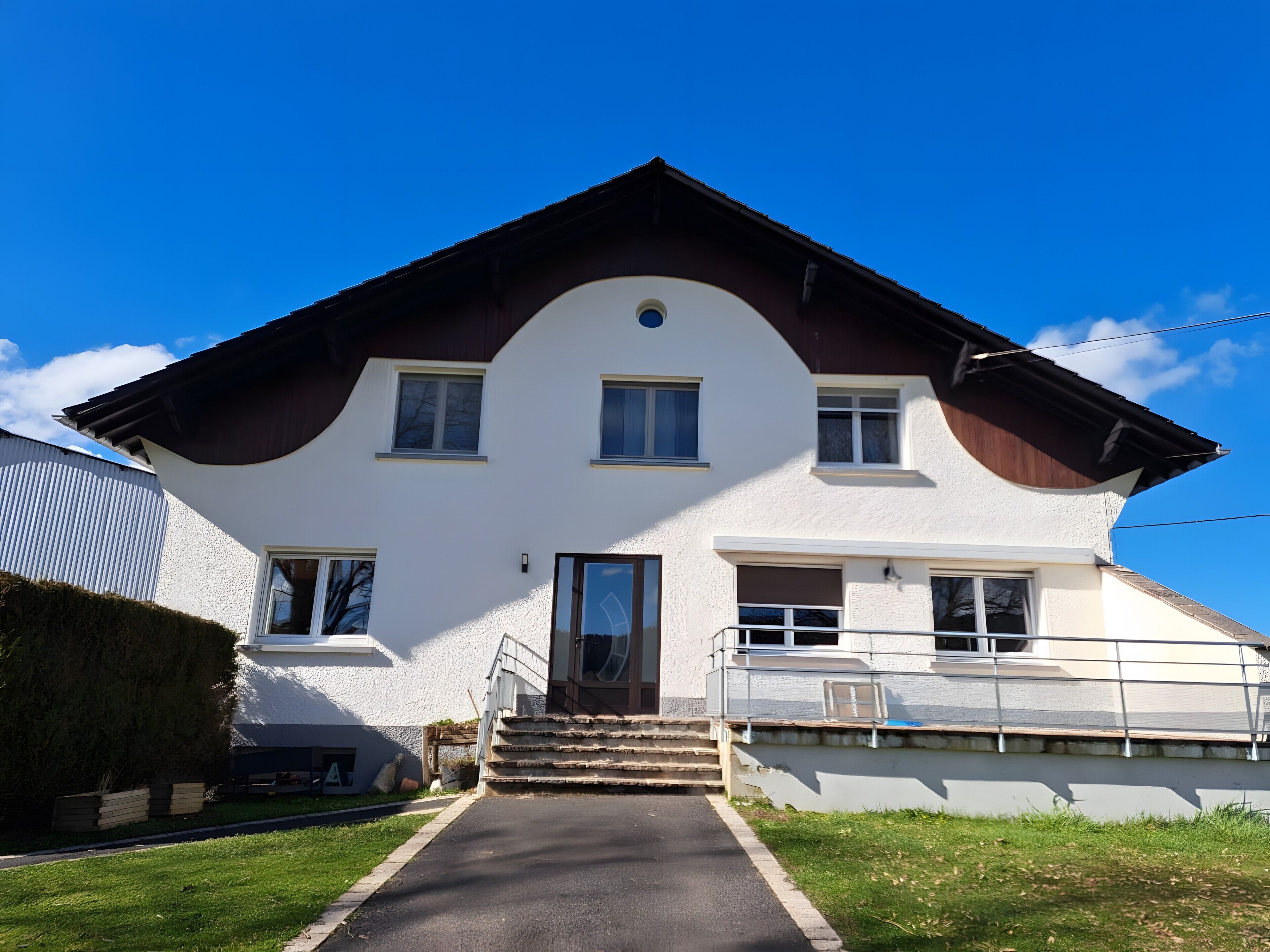 A two-story house with a front entrance, a staircase, and a clear sky.