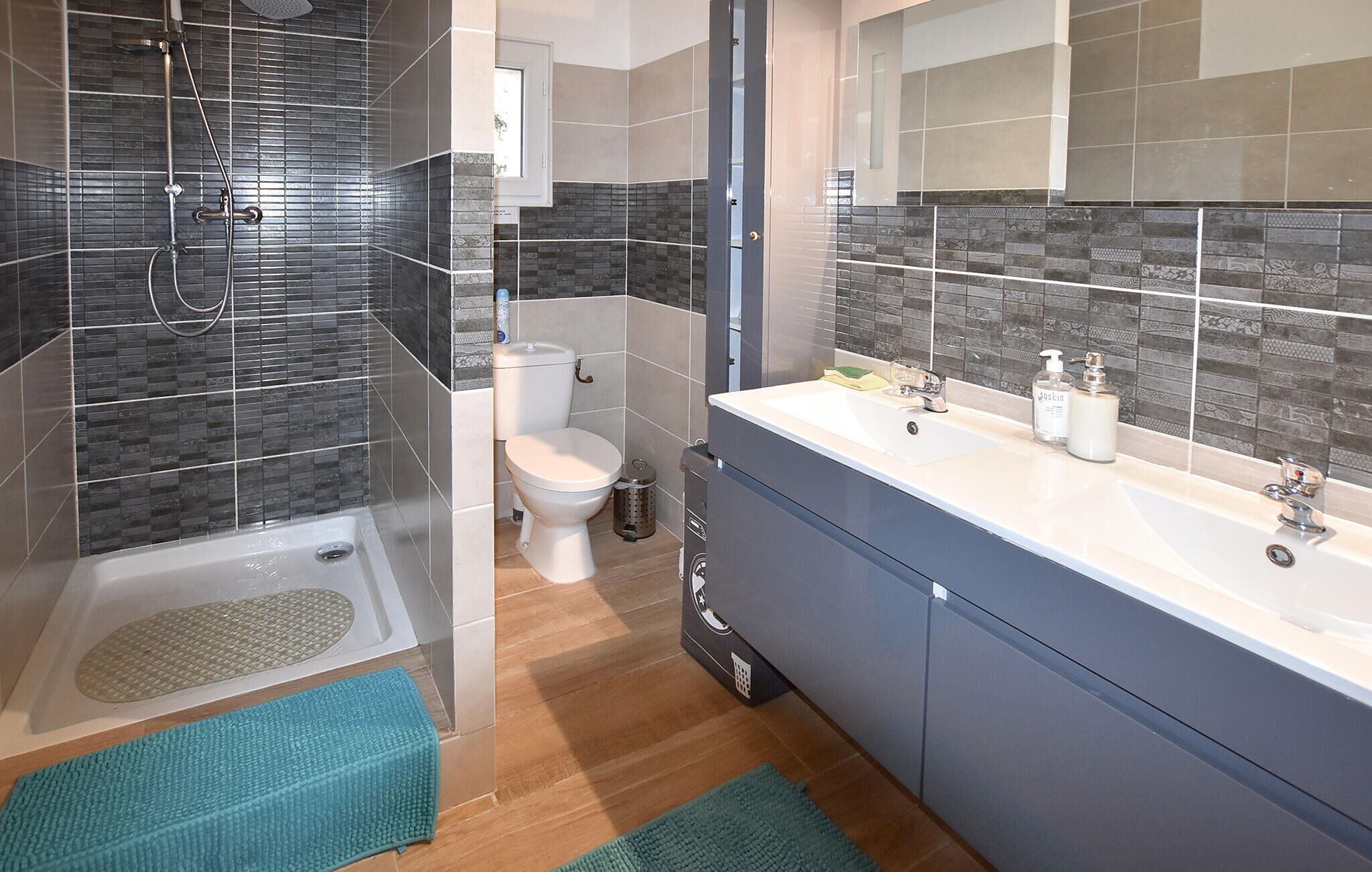Une salle de bain moderne équipée d’une douche, de toilettes et d’un meuble-lavabo.