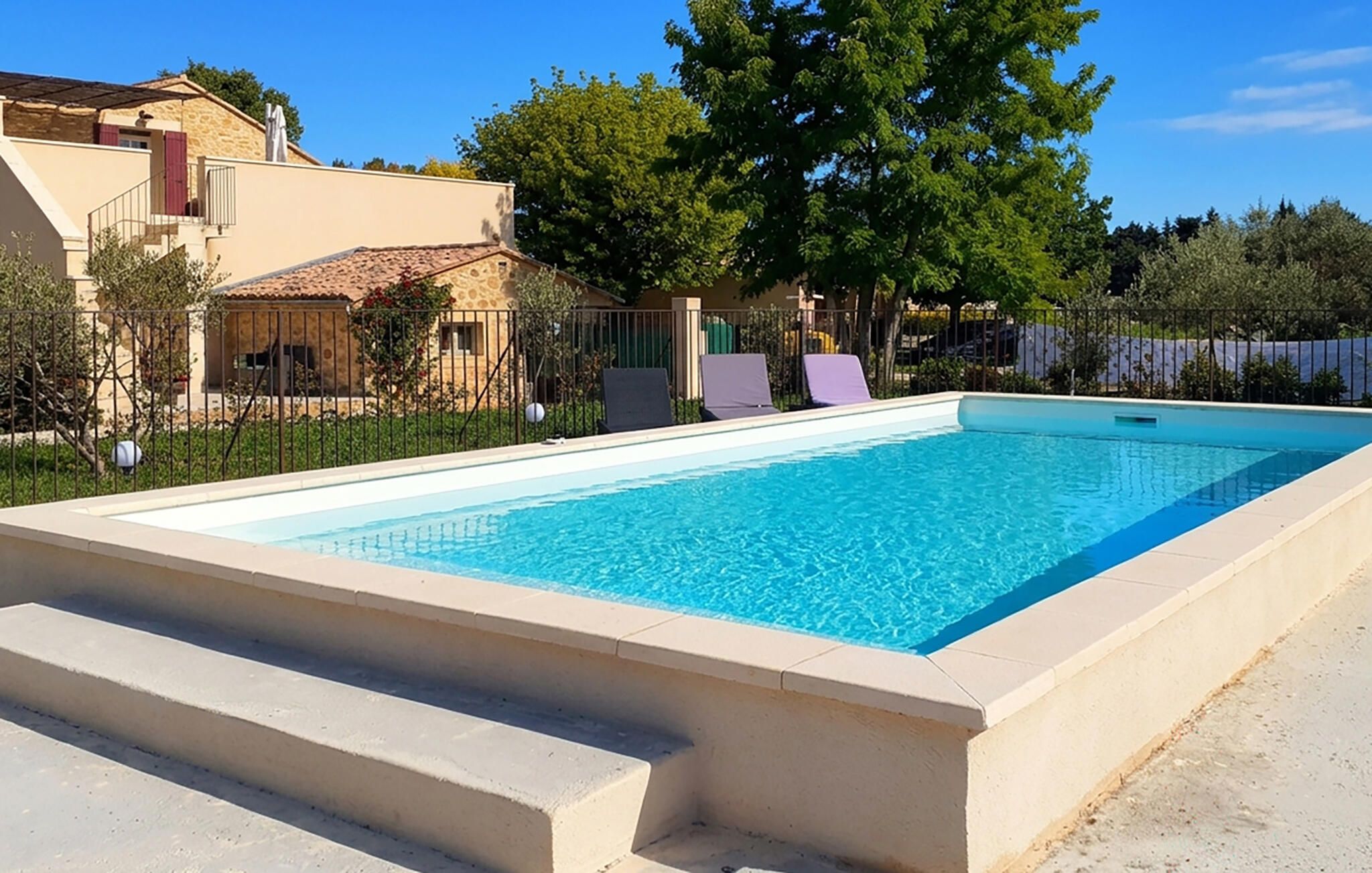 A rectangular swimming pool with a concrete border and steps leading into it.