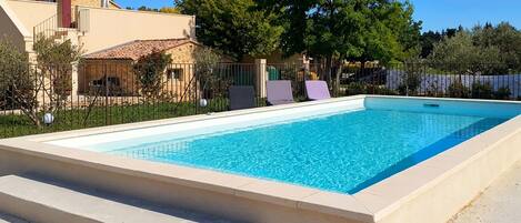 A rectangular swimming pool with a concrete border and steps leading into it.