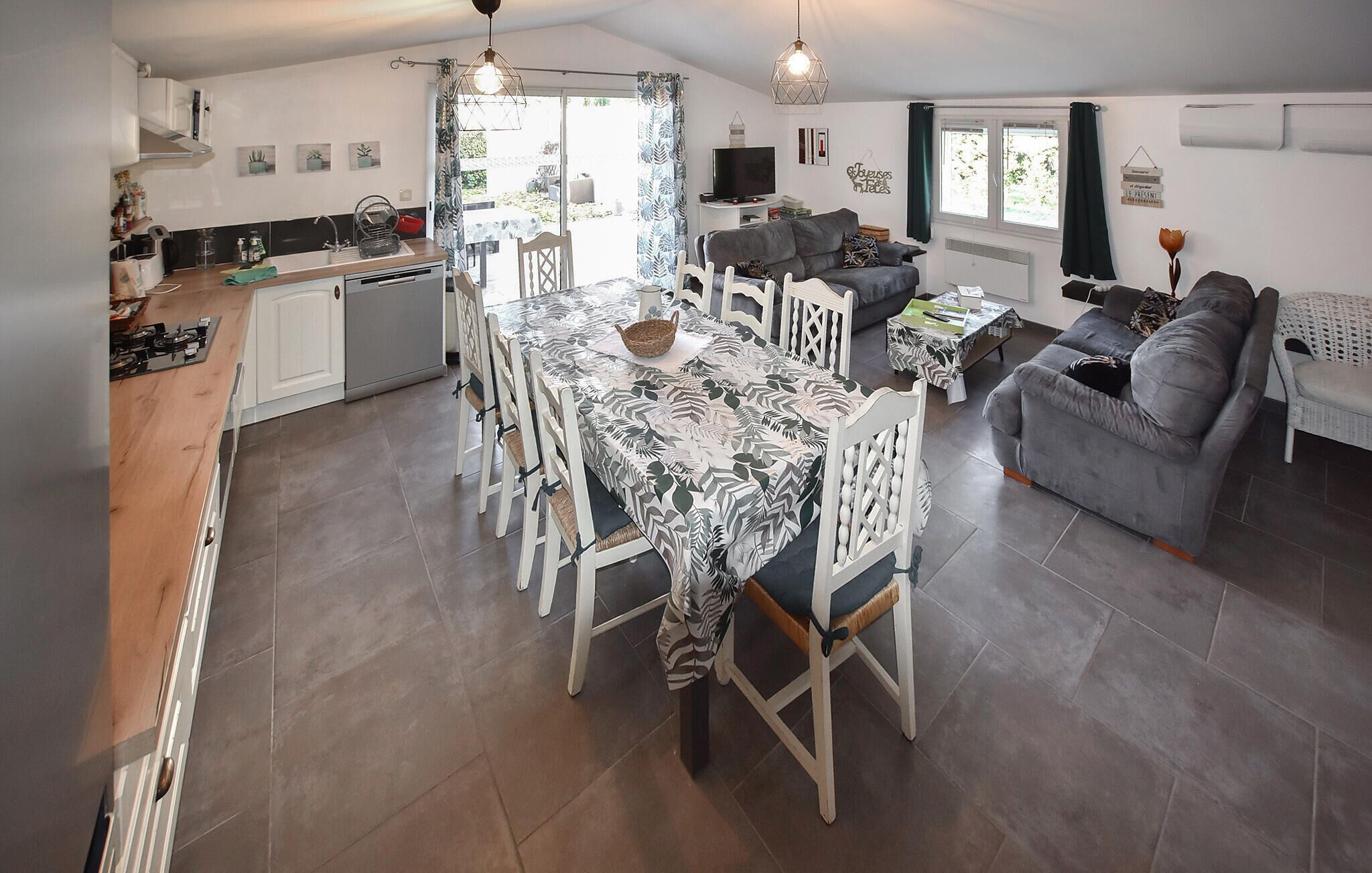 Amplia sala de estar con mesa de comedor, sillas, sofá y televisor.
