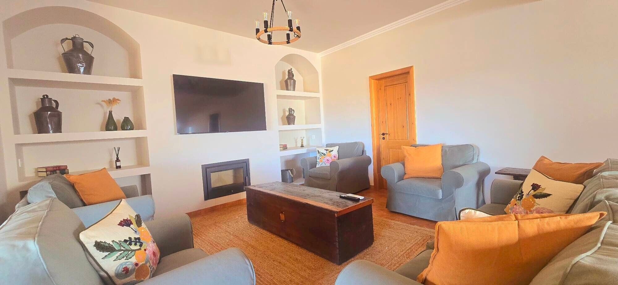 A living room with a fireplace, sofas, a coffee table, and a TV mounted on the wall.