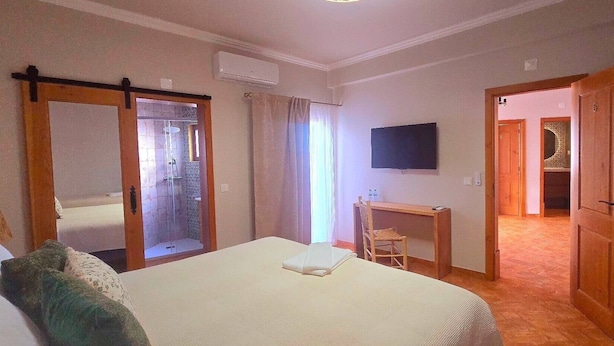 A hotel room with a bed, a desk, a TV, and a shower area. - Villa 'Casas Do Monte I - T3' with Shared Pool, Private Terrace and Wi-Fi (Moinhos de vento)