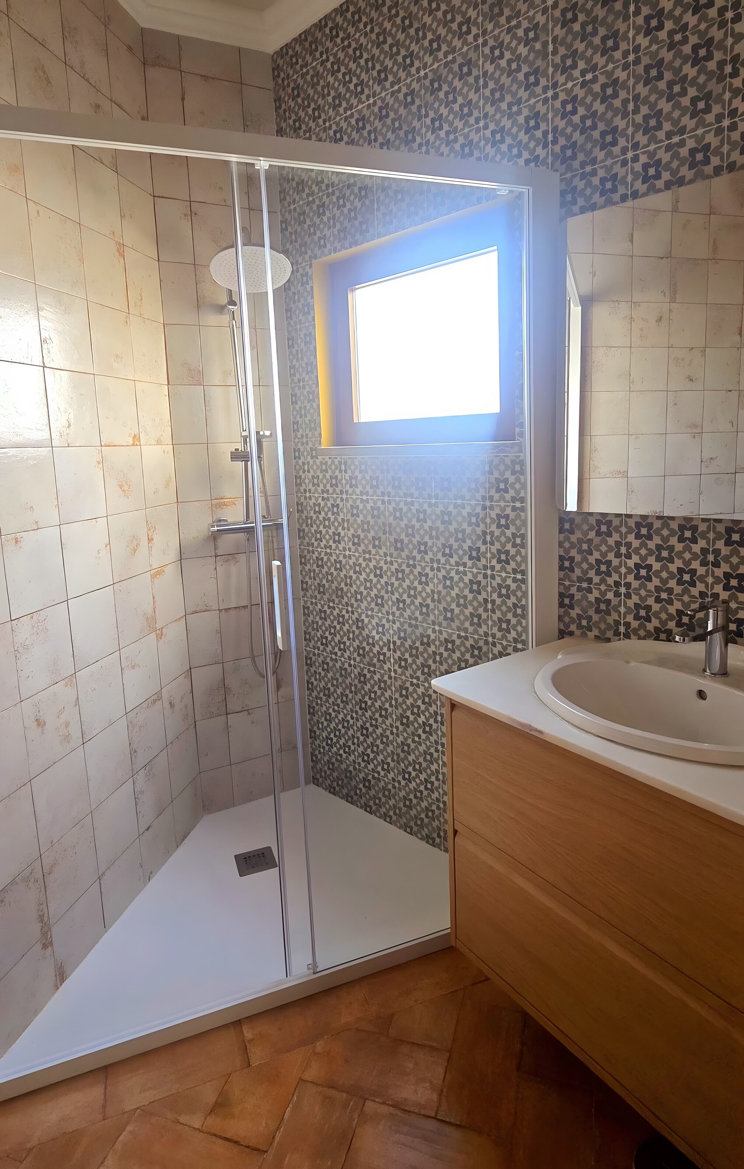 Un baño con ducha, lavamanos y ventana.