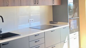 A modern kitchen with wooden cabinets, a white countertop, and a built-in refrigerator. - Villa 'Casas Do Monte I - T3' with Shared Pool, Private Terrace and Wi-Fi (Moinhos de vento)