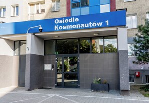 Ein Gebäudeeingang mit einem blauen Schild, auf dem 'Osiedle Kosmonautów 1' steht.