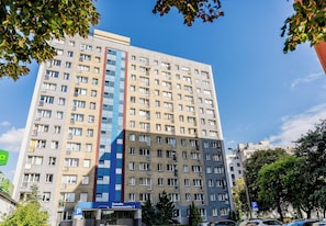 Ein mehrstöckiges Hotel mit einer zentralen, blauen Glasfassade, mehreren Balkonen und einem Schild, das freie Parkplätze anzeigt.