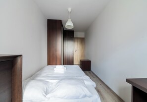 Een hotelkamer met een bed, een nachtkastje, een kledingkast en een hanglamp.