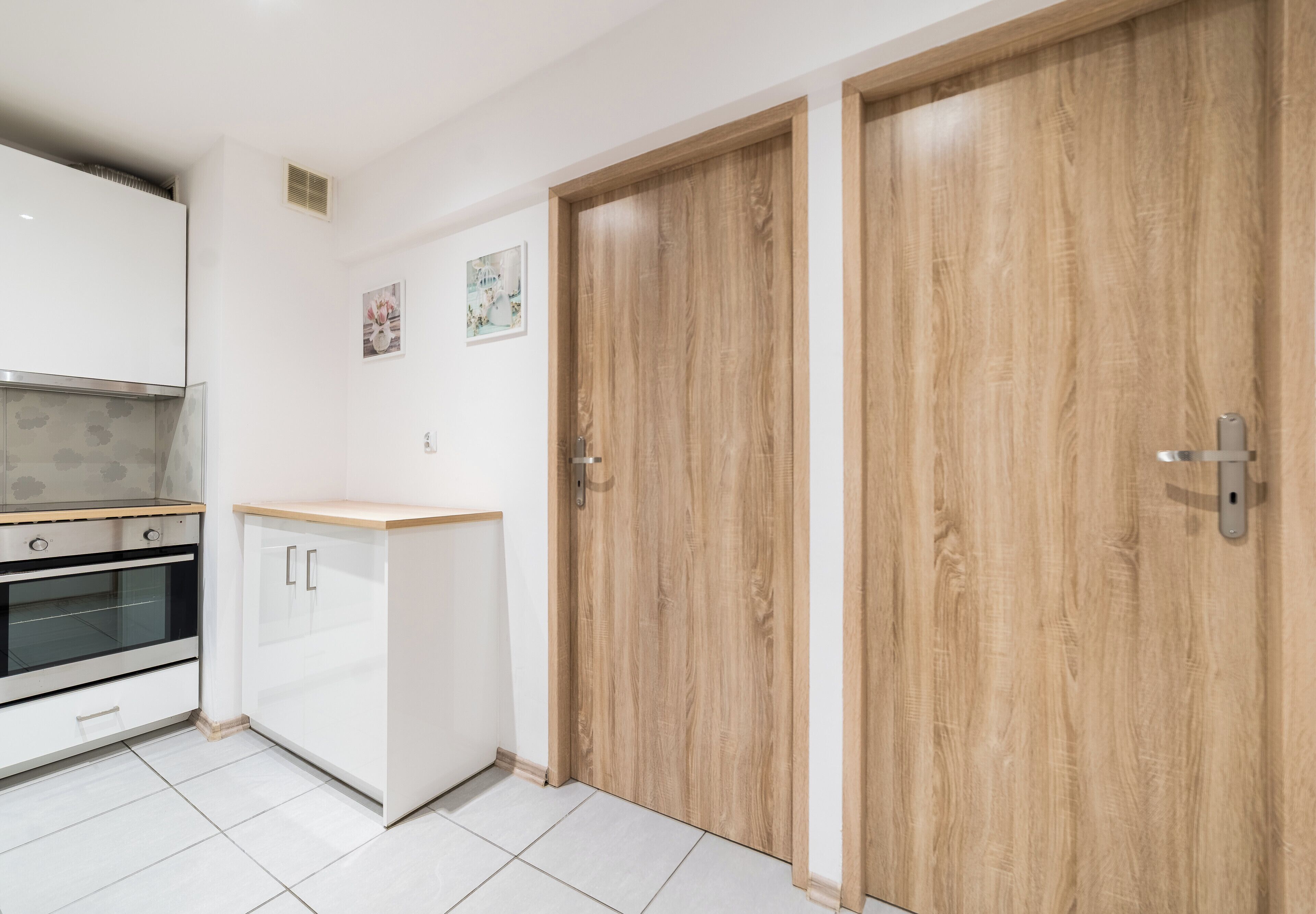 A kitchen with a built-in oven, a white cabinet, and a wooden door.