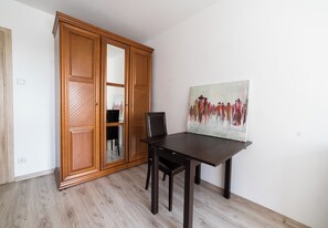Ein Essbereich mit einem Holztisch und Stühlen, einem Gemälde an der Wand und einem Schrank aus Holz mit Spiegel.
