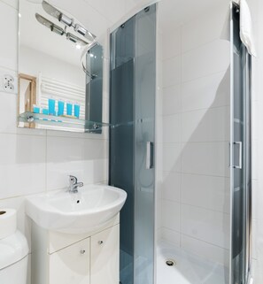 Ein modernes Badezimmer mit Waschbecken, Spiegel und Duschkabine aus Glas.