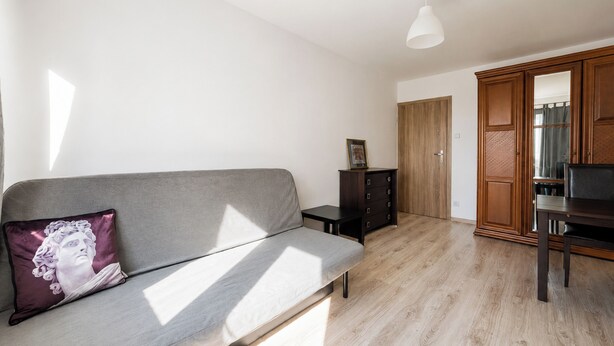 Una sala de estar moderna con un sofá gris, una mesita auxiliar, un armario de madera y una lámpara de techo.