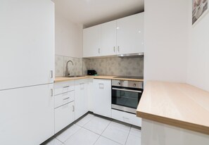 Een moderne keuken met witte kasten, een roestvrijstalen oven en een houten aanrecht.