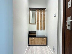 Ein Flur mit einem Holzschrank, einem Spiegel und einem Kleiderhaken.