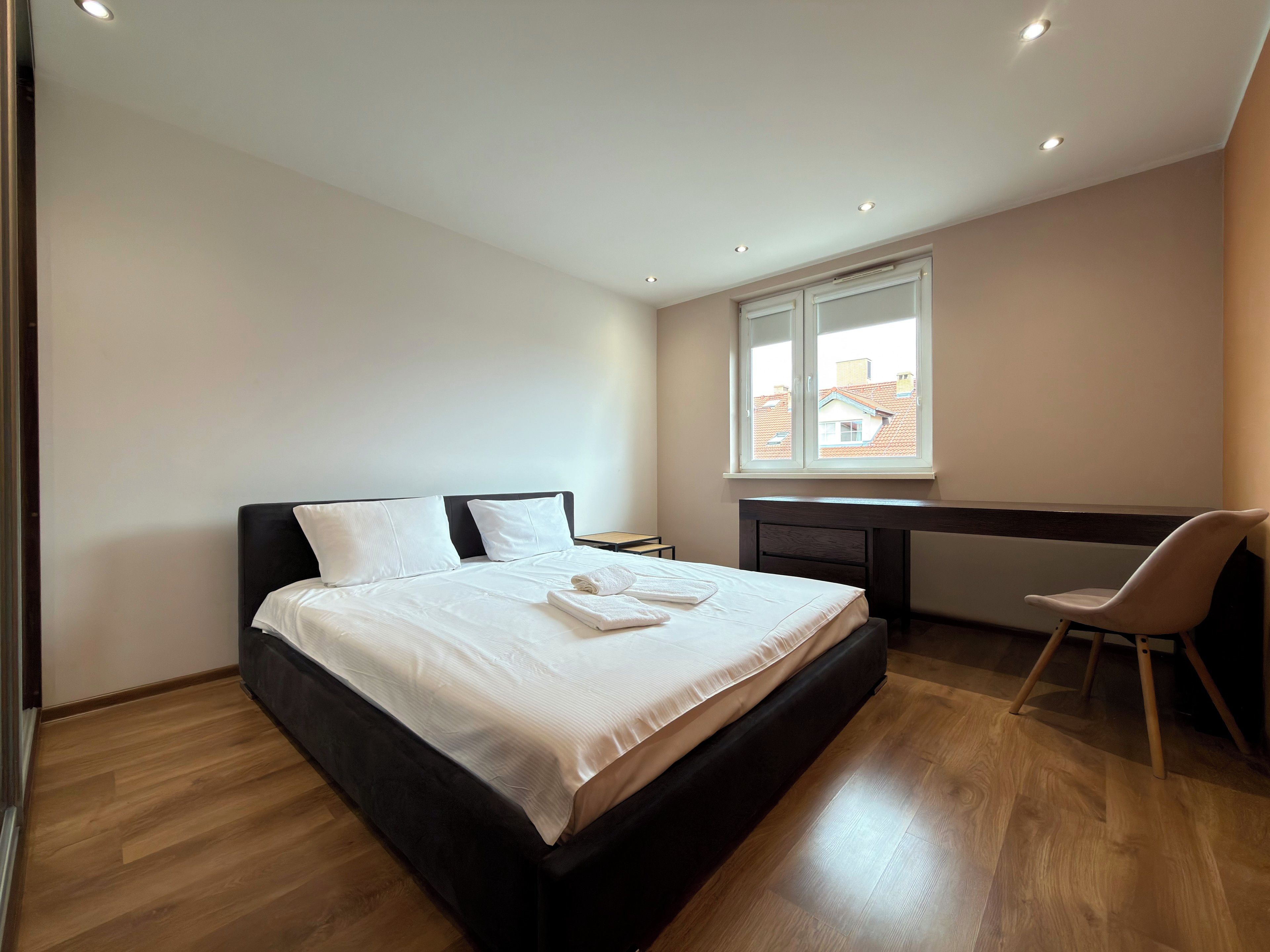 A modern bedroom with a large bed, a desk, and a chair.
