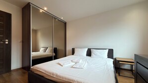 Moderni hotellihuone, jossa on suuri sänky, vaatekaappi ja pieni työpöytä.