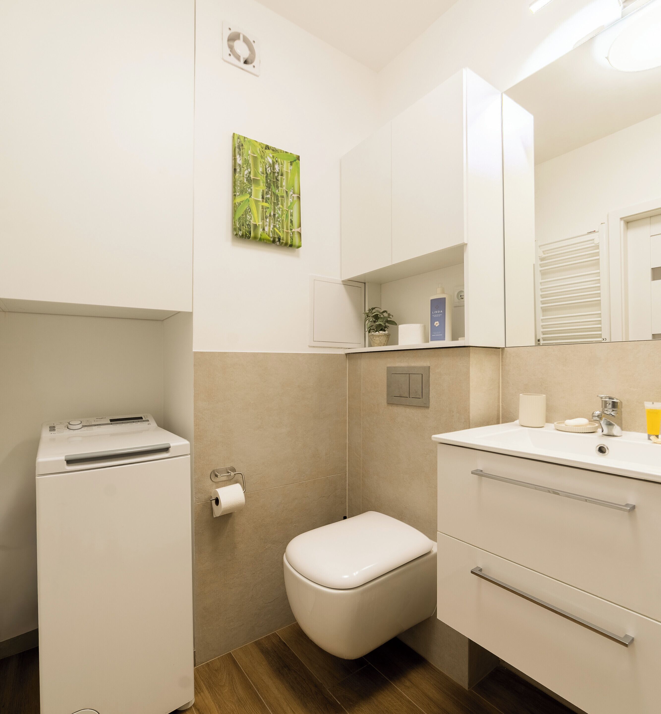 A compact bathroom with a toilet, sink, and a small cabinet with toiletries.