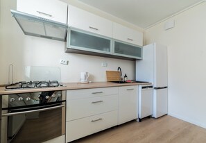 A modern kitchen with a gas stove, oven, white cabinets, a built-in microwave, and a refrigerator. - Grunwald Homely Apartment (Poznań)