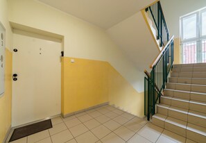 Eine Treppe mit einer gelben Wand, einer weißen Tür und einem grünen Geländer.