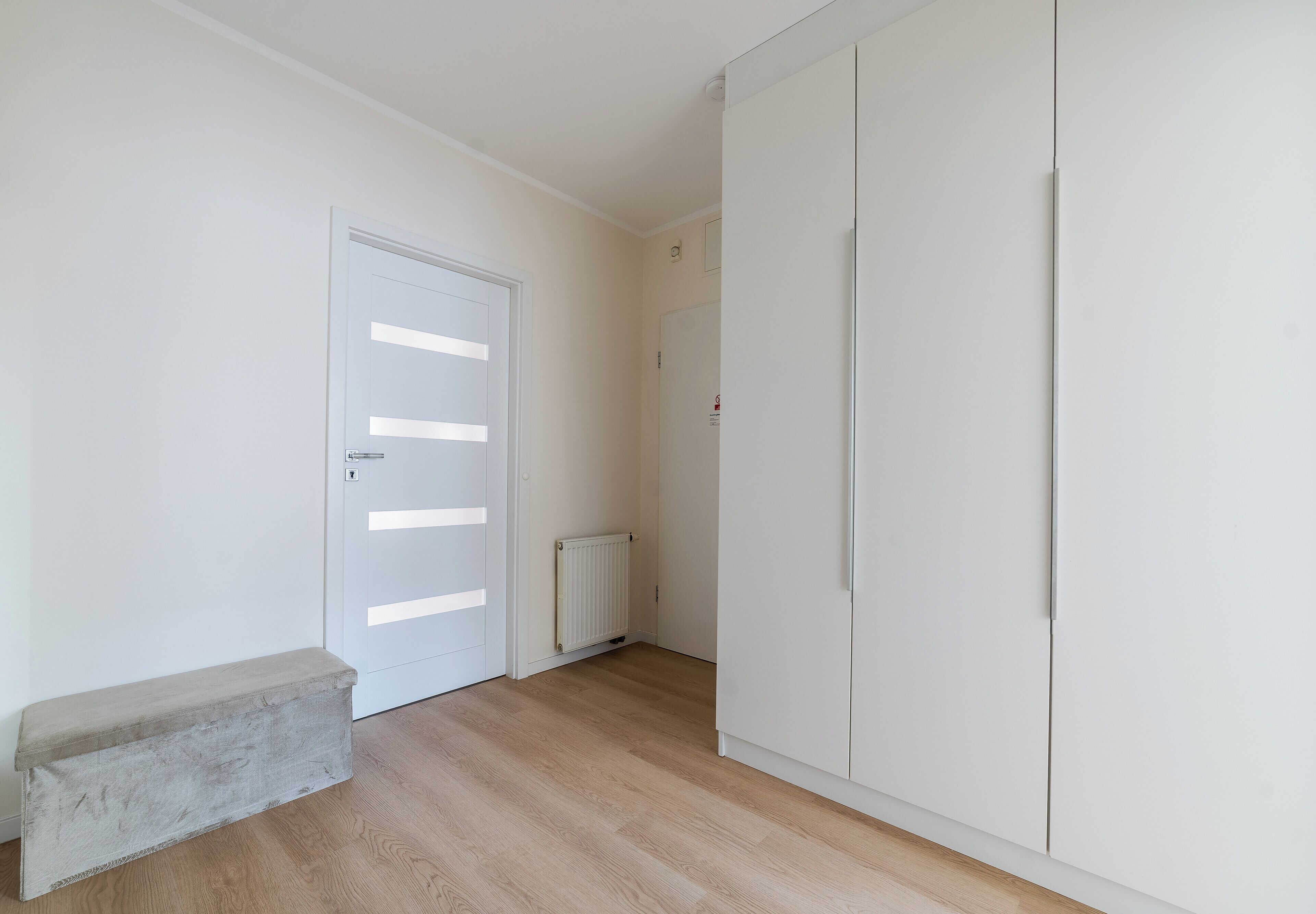 Une pièce avec une porte blanche, un radiateur et une armoire.