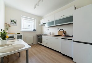 A modern kitchen with white cabinetry, a built-in oven, and a dishwasher. - Grunwald Homely Apartment (Poznań)