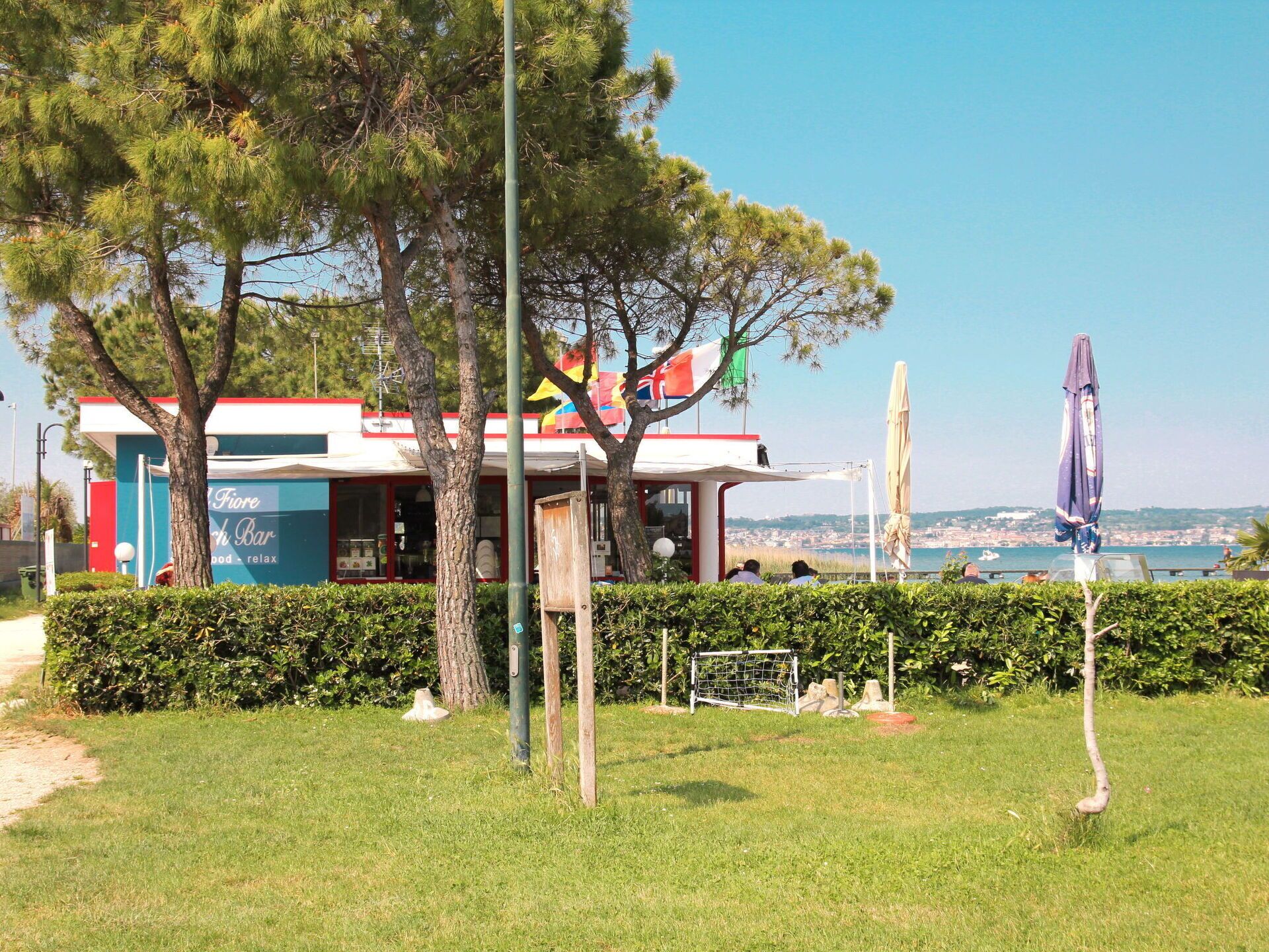 A restaurant with outdoor seating, a view of the sea, and a flag on top.