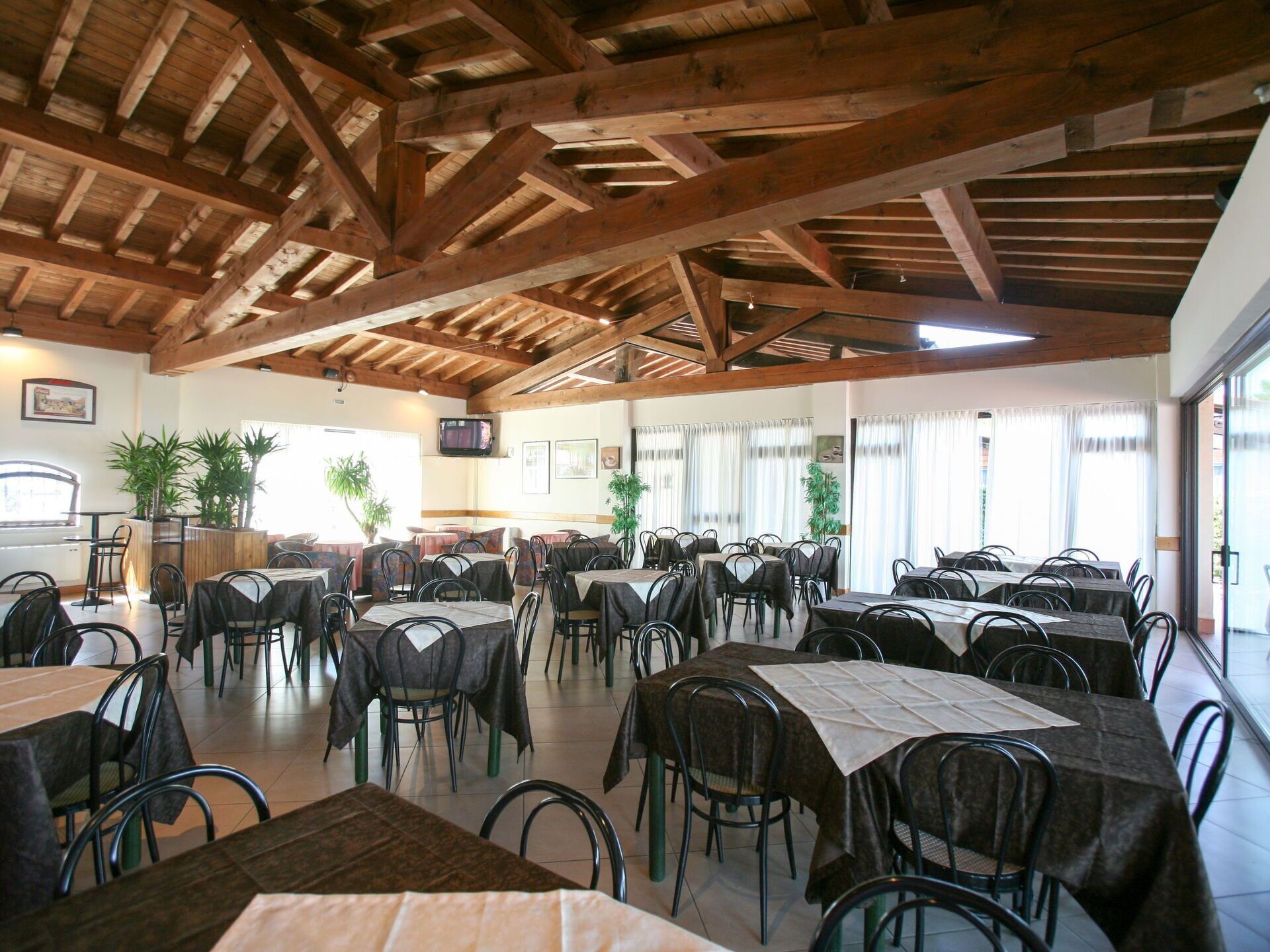 Un vaste espace dédié à la salle à manger, avec de hauts plafonds en bois, ainsi que de nombreuses tables et chaises.