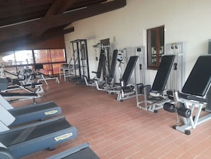Ein Fitnessstudio mit Laufbändern, Krafttrainingsgeräten und Kurzhanteln.