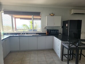 A kitchen with white cabinets, a black countertop, a sink, a microwave, and a refrigerator.