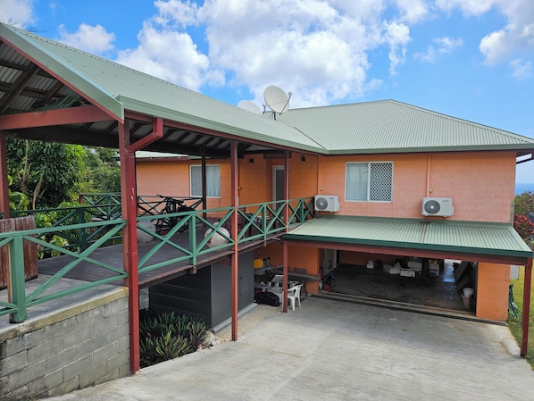 A two-story building with a covered porch, satellite dish, and air conditioning units.