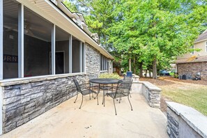 A covered patio area with a stone wall, outdoor furniture, and a view of the neighborhood. - Auburn - 3 King Beds - 3 Private Baths - Near Downtown AU!! (Auburn)