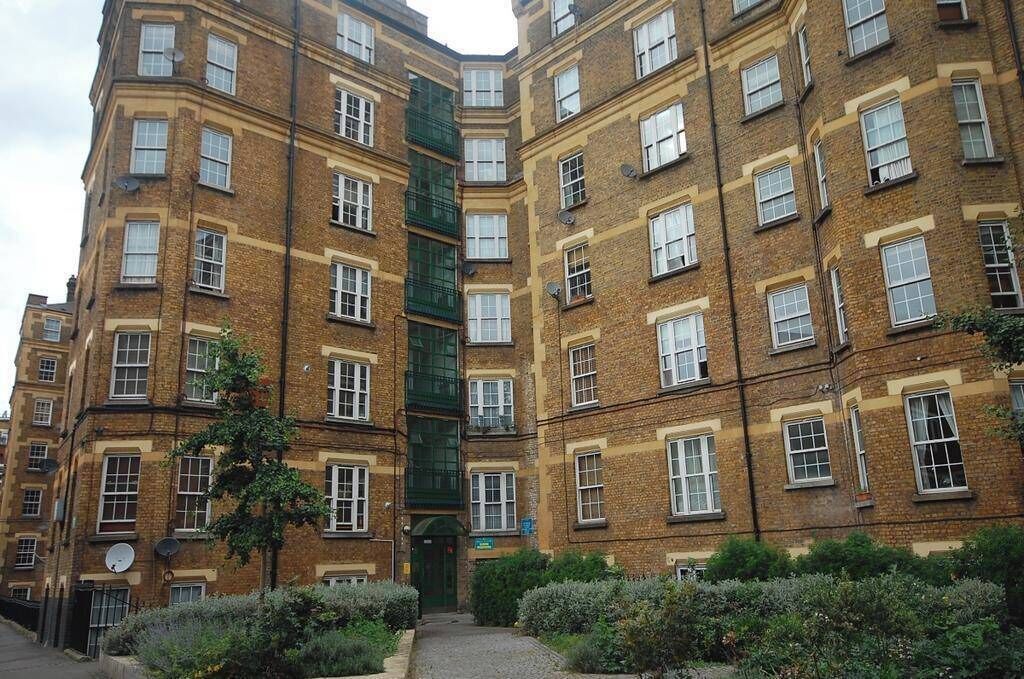 A multi-story residential building with a brick facade, multiple windows, and a central entrance.
