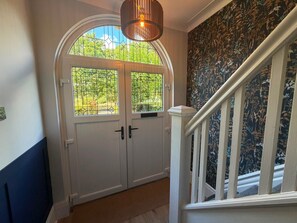 A hallway with a white door, a staircase with white railings, and a floral wallpaper. - 3 bedroom Apartment 2 up to 5 people Free parking (Blackpool)